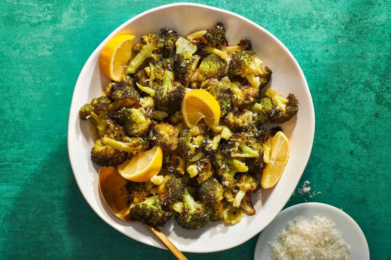 En skål med ugnsrostad broccoli, garnerad med citronklyftor och riven parmesan. Perfekt för att koka broccoli på ett smakrikt sätt.