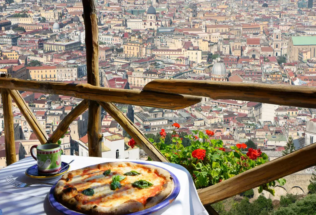 Pyszna pizza na stole z widokiem na Neapol. Zastanawiasz się, ile kosztuje pizza we Włoszech?