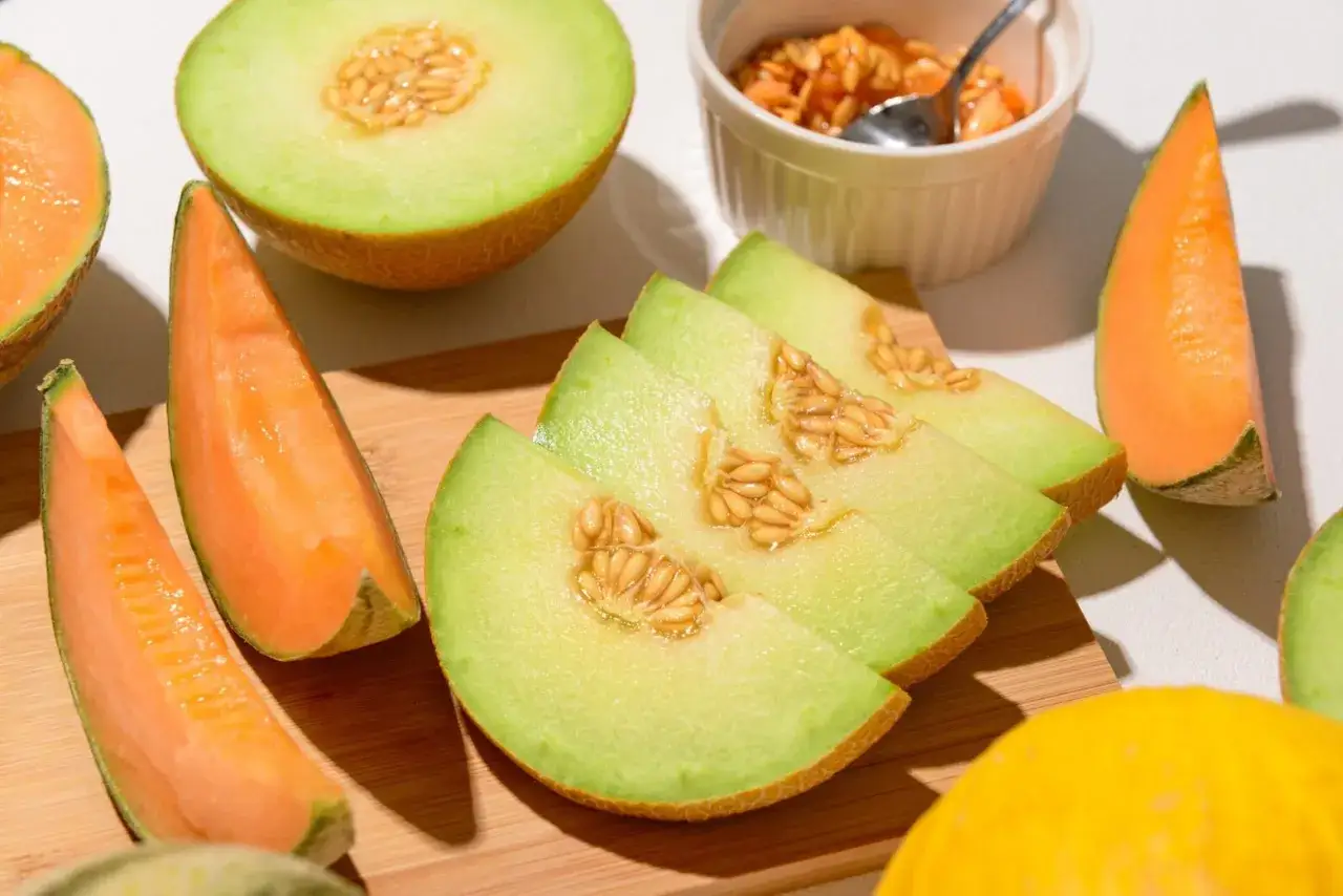 Skivor av galiamelon och cantaloupe, med fr&ouml;n synliga. En sk&aring;l med melonbitar och en sked. L&aring;gt galiamelon kcal-inneh&aring;ll g&ouml;r den till ett h&auml;lsosamt val.