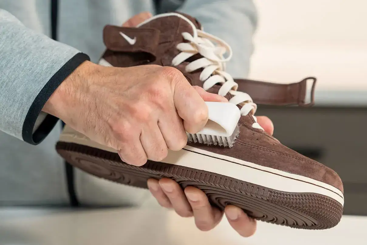 Main tenue de votre chaussure en daim. Un homme utilise une brosse pour l'entretien de sa chaussure en daim marron.