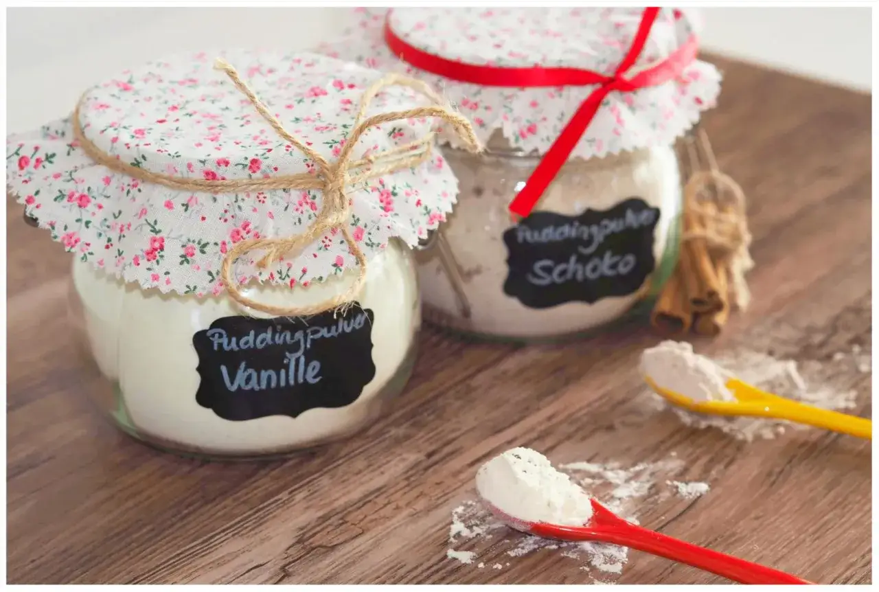 Zwei Gl&auml;ser mit selbstgemachtem Vanillepuddingpulver und Schokopuddingpulver, verziert mit Stoff und Schnur.
