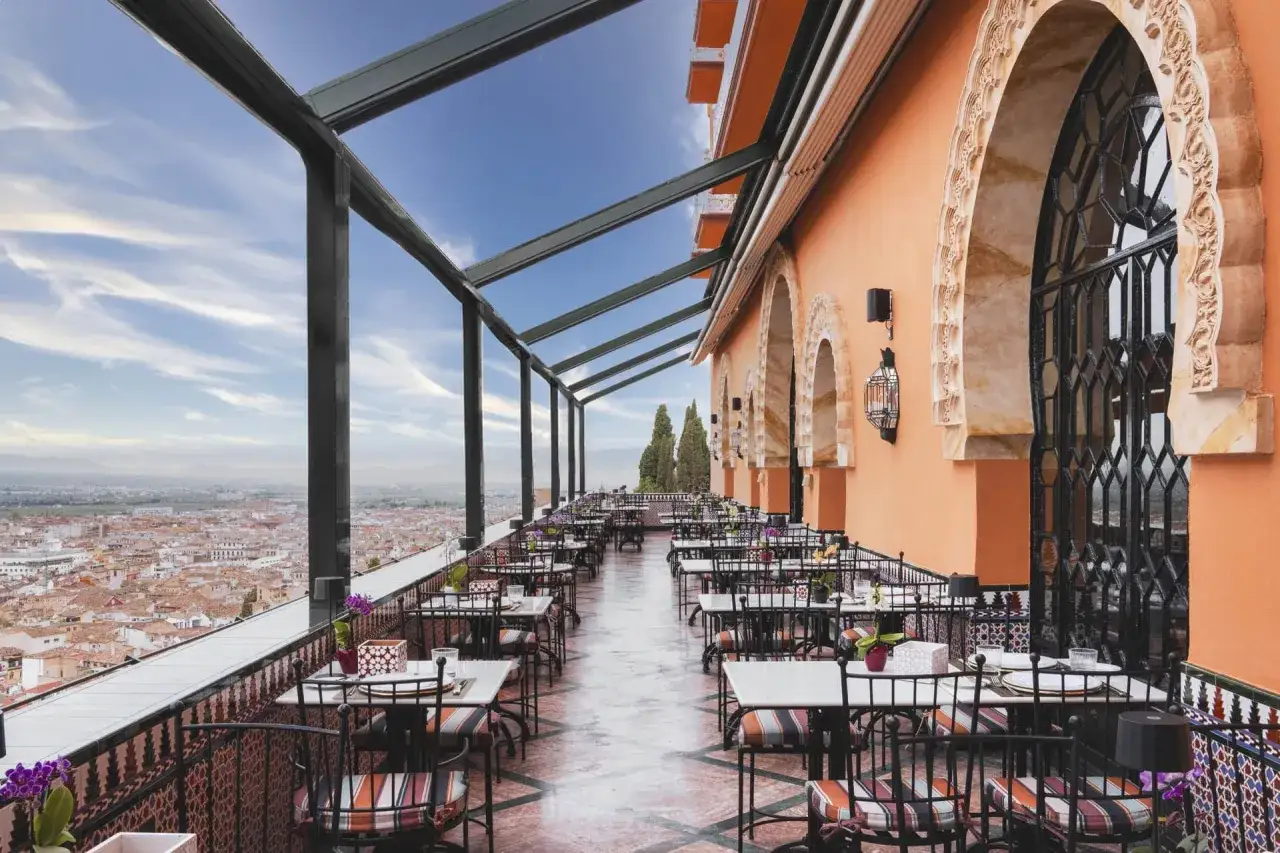 Terrasse mit Blick auf Granada, ein echter Geheimtipp f&uuml;r ein Abendessen. Bunte St&uuml;hle und Tische laden zum Verweilen ein.