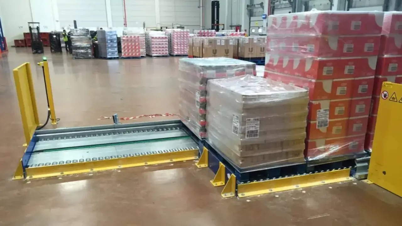 Magazyn z paletami towarów, systemem przenośników i żółtą osłoną. Efektywne rozwiązanie do **cross docking**.