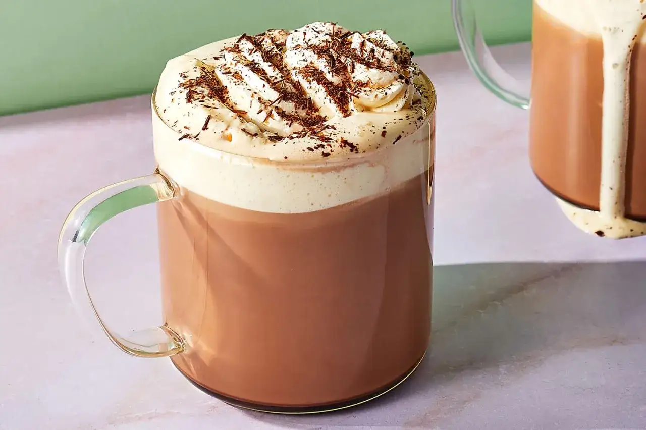 Caffè mocha rezepte: Ein cremiger Kaffee-Kakao-Traum mit Schlagsahne und Schokostreuseln in einer Glas Tasse.