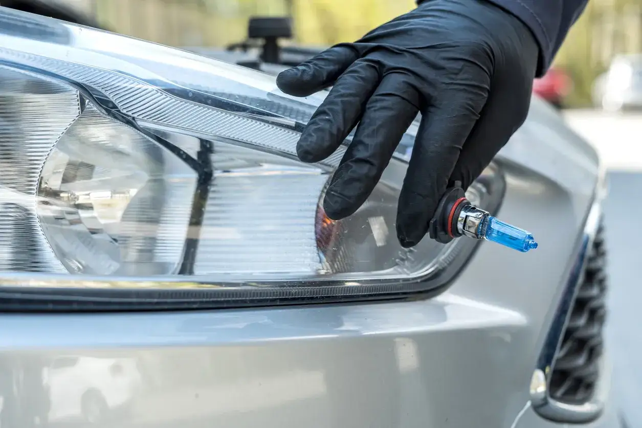 Main tenant une ampoule halogène bleue pour un phare de voiture.