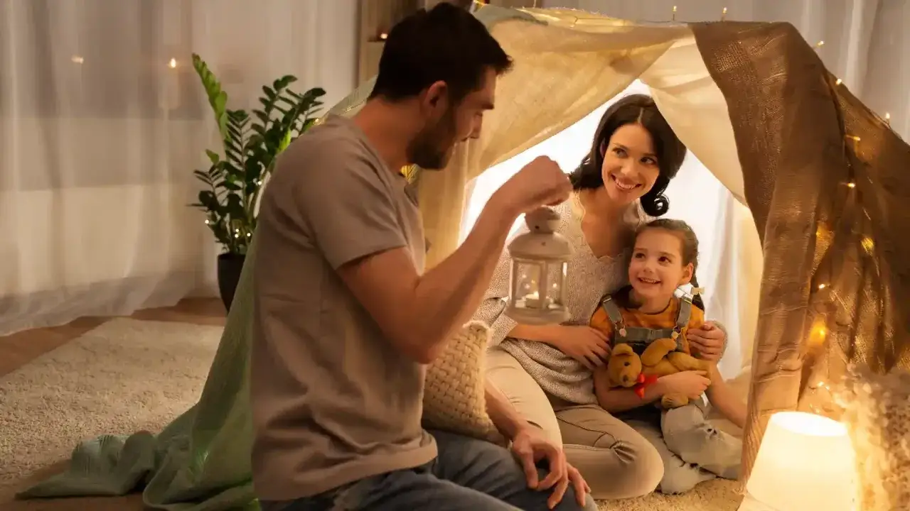 Familie im selbstgebauten Zelt, Vater h&auml;lt Laterne. Eine hochsensibel Mama genie&szlig;t die Geborgenheit mit ihrem Kind.