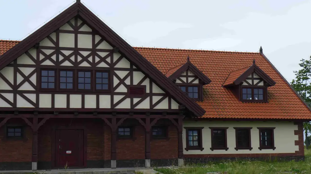 Elewacja budynku w stylu mur pruski, z drewnianą konstrukcją szachulcową i ceglanym cokołem.