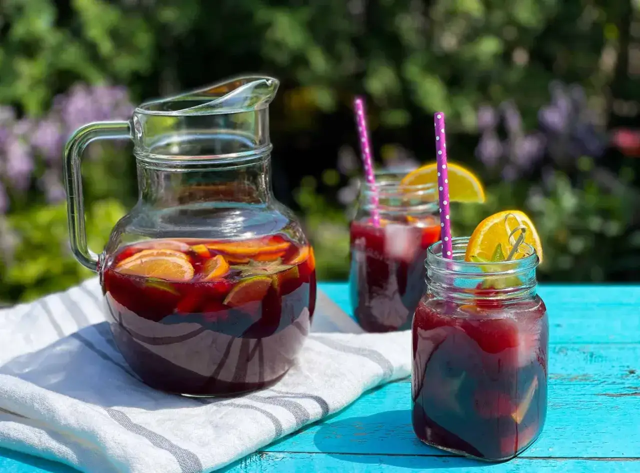 Carafe et verres de sangria rouge fruit&eacute;e, parfaits pour une recette estivale.