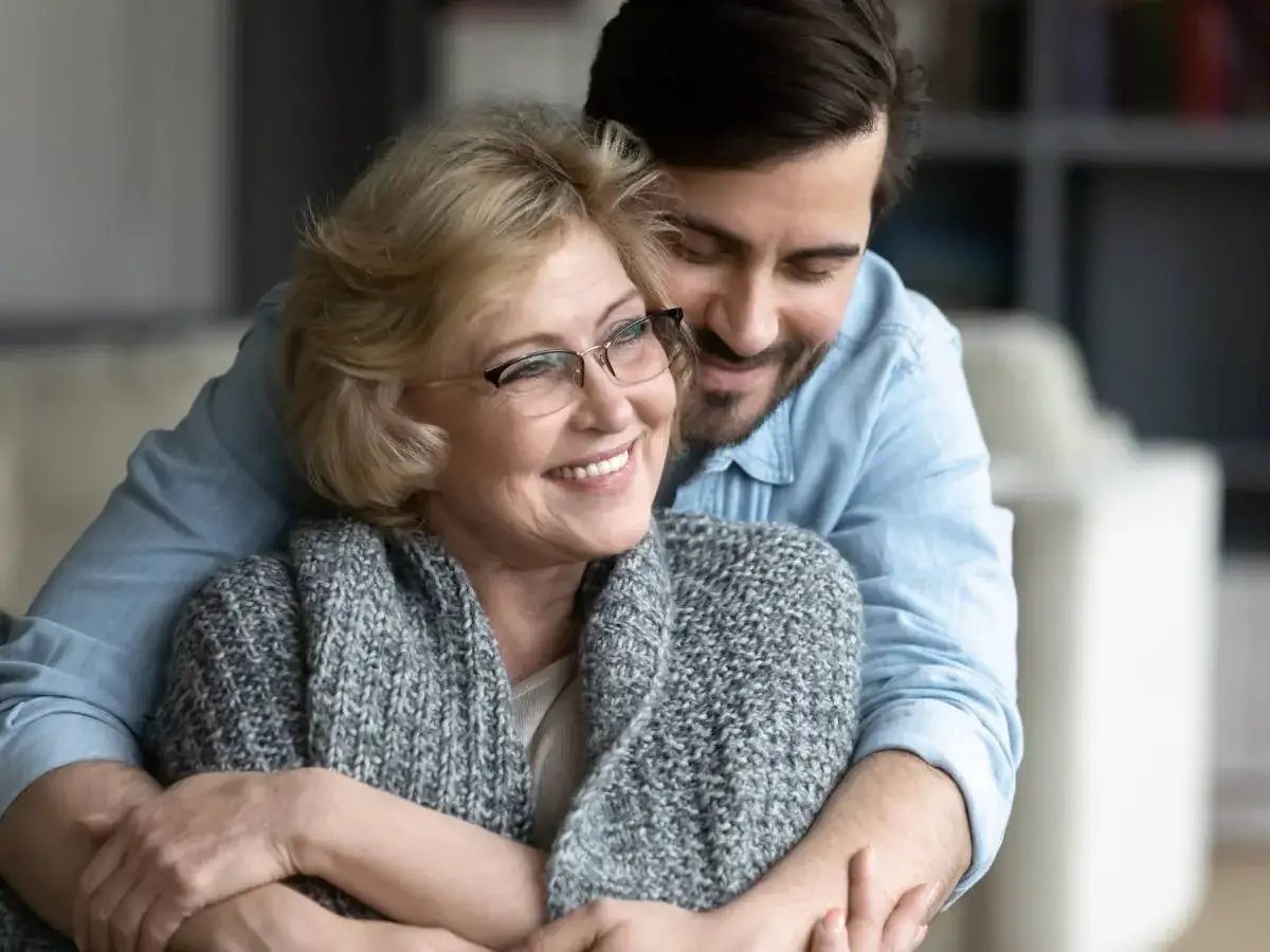Un abbraccio affettuoso tra madre e figlio adulto. La serenit&agrave; sul volto di lei, nonostante l'ansia per i figli grandi, &egrave; palpabile.