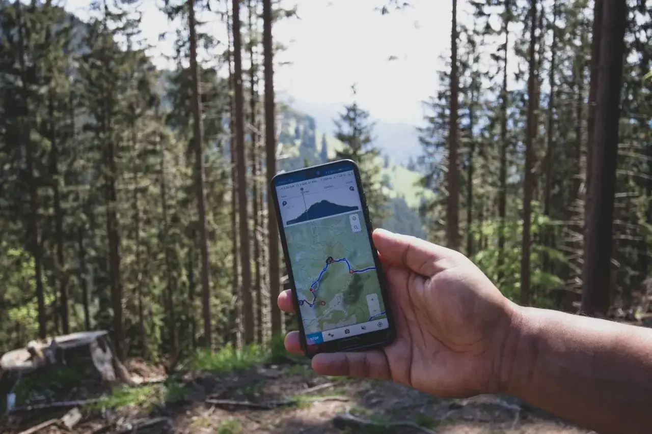 Turysta z telefonem i mapą w górach, powerbank w plecaku