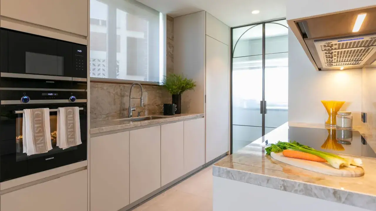 Cocina moderna con electrodomésticos integrados, encimera de mármol y detalles que inspiran los mejores estudios interiorismo.