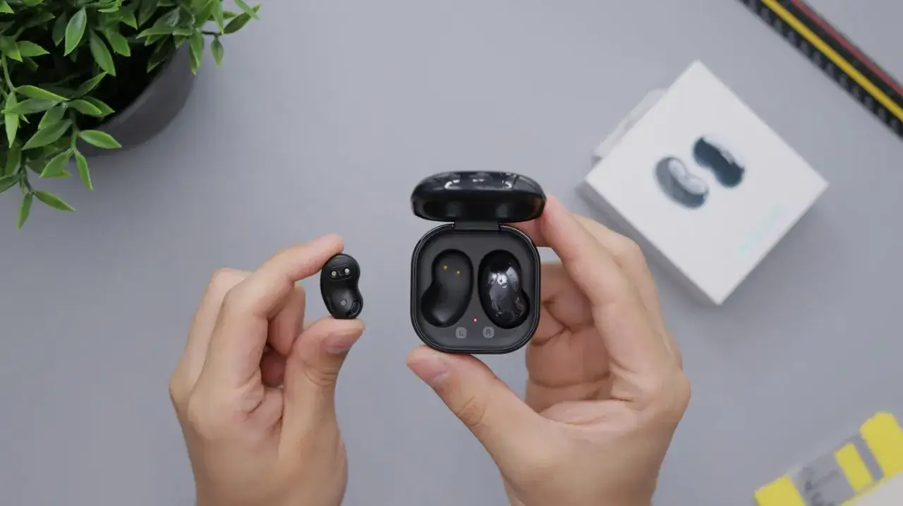 H&auml;nde halten schwarze Kopfh&ouml;rer und Ladecase. So einfach lassen sich die AirPods verbinden.