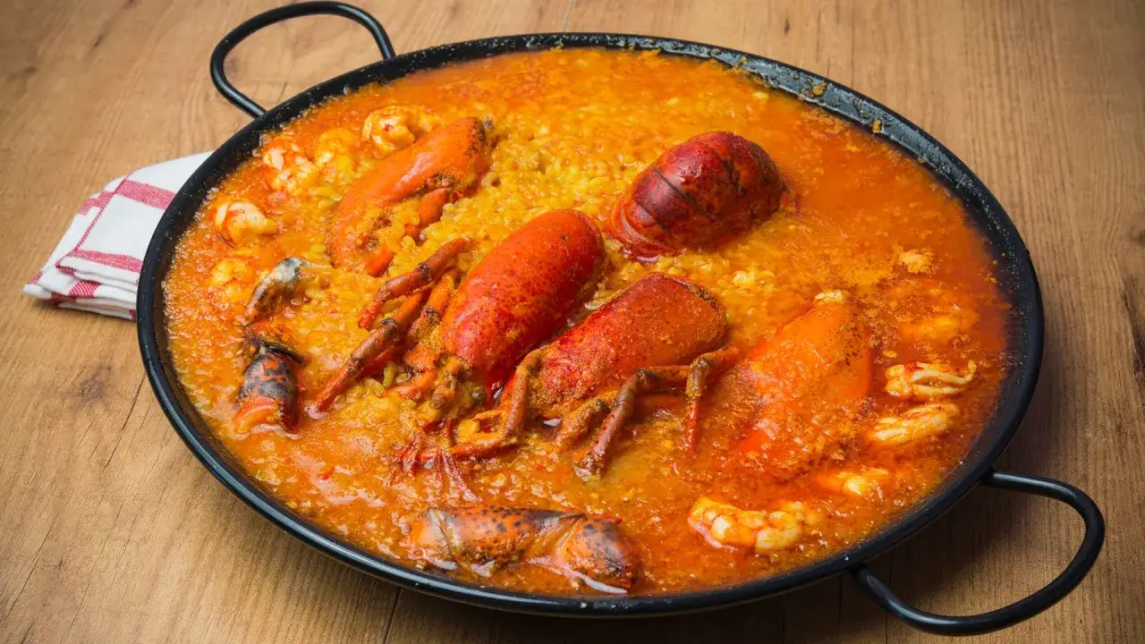 Arroz con bogavante, un plato de marisco vibrante con langostas enteras y gambas en una sabrosa salsa de tomate y arroz.