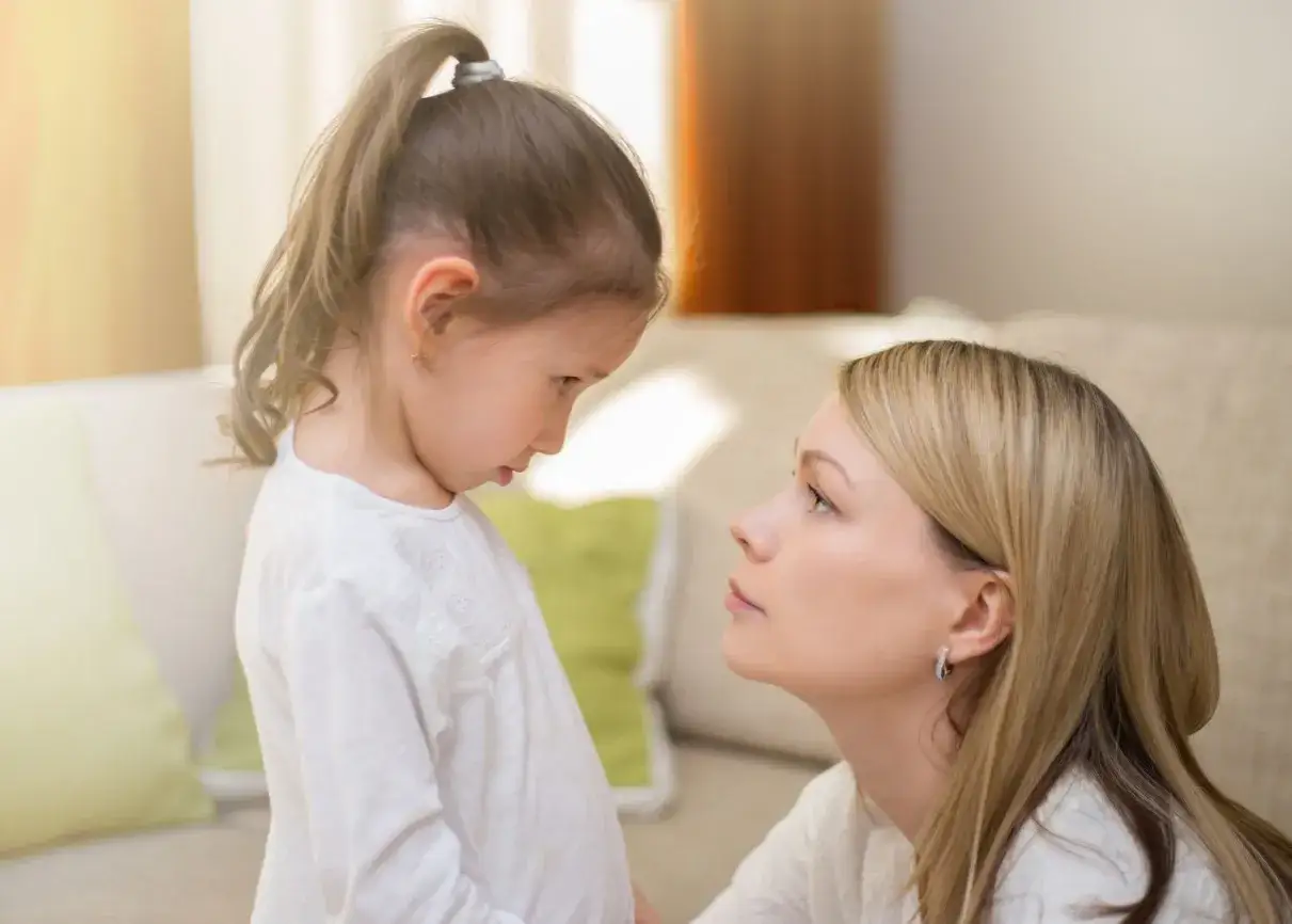 Mama rozmawia z córką, która ma problem z hiperfiksacją. Dziecko patrzy w dół, mama z troską.