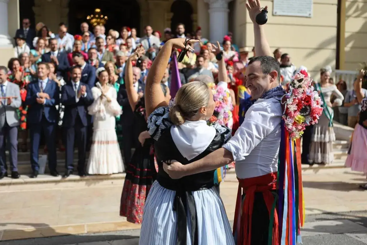 Pareja bailando flamenco, celebrando las tradiciones de M&aacute;laga. Ella con vestido blanco y negro, &eacute;l con camisa blanca y faja roja.