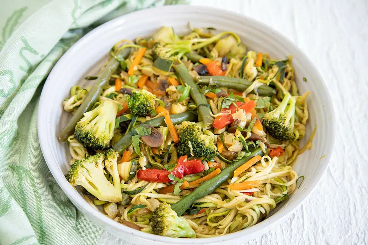 Buntes Gem&uuml;se mit Zucchini-Spaghetti kochen oder braten: Brokkoli, Karotten, gr&uuml;ne Bohnen und Pilze in einer Sch&uuml;ssel.