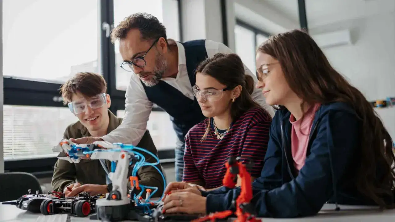 Ragazzi e insegnante lavorano a un progetto robotico, mostrando come funziona l'alternanza scuola lavoro in un ambiente pratico e stimolante.
