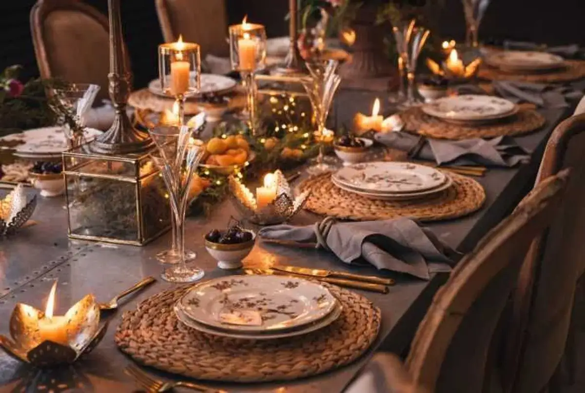 Élégante deco table nouvel an nature : bougies, vaisselle fleurie, nattes en jonc de mer et feuillages créent une ambiance chaleureuse et festive.