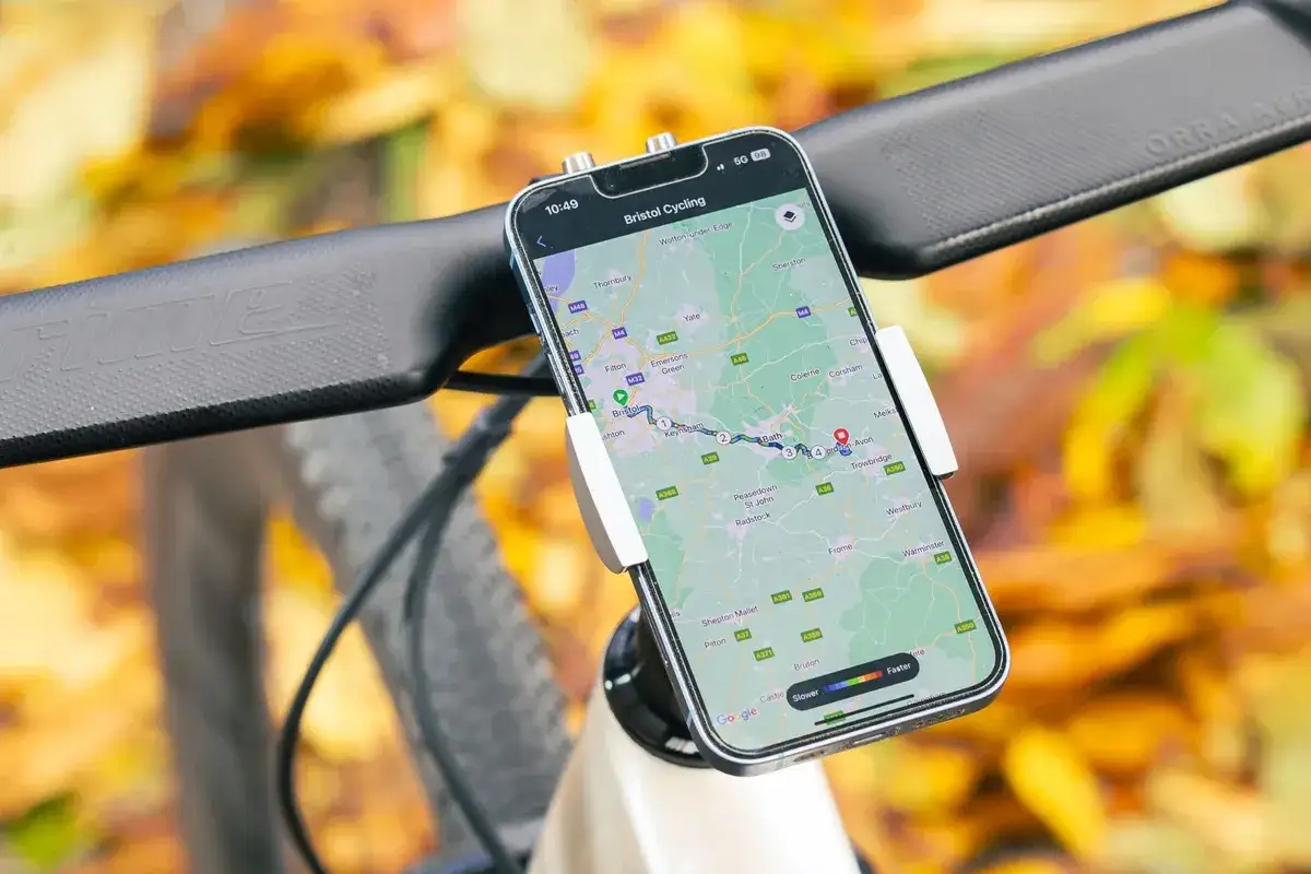 Na kierownicy roweru zamontowany jest smartfon z mapą trasy rowerowej. To nowoczesny licznik na rower, który pokazuje drogę przez malownicze tereny.
