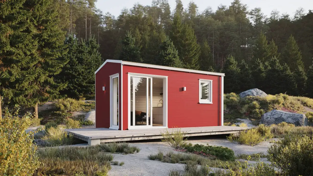 Röd friggebod med stora fönster och altan, placerad i en skogsglänta. Perfekt för den som vill flytta friggebod till naturen.