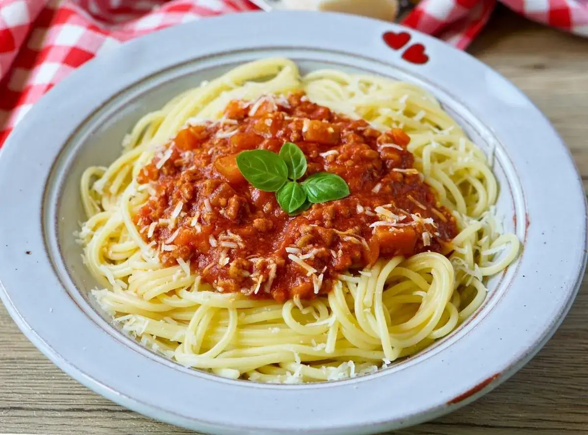 Teller mit Spaghetti Bolognese, bestreut mit Parmesan und garniert mit Basilikum. Perfekt für schnelle Bolognese für Kinder.