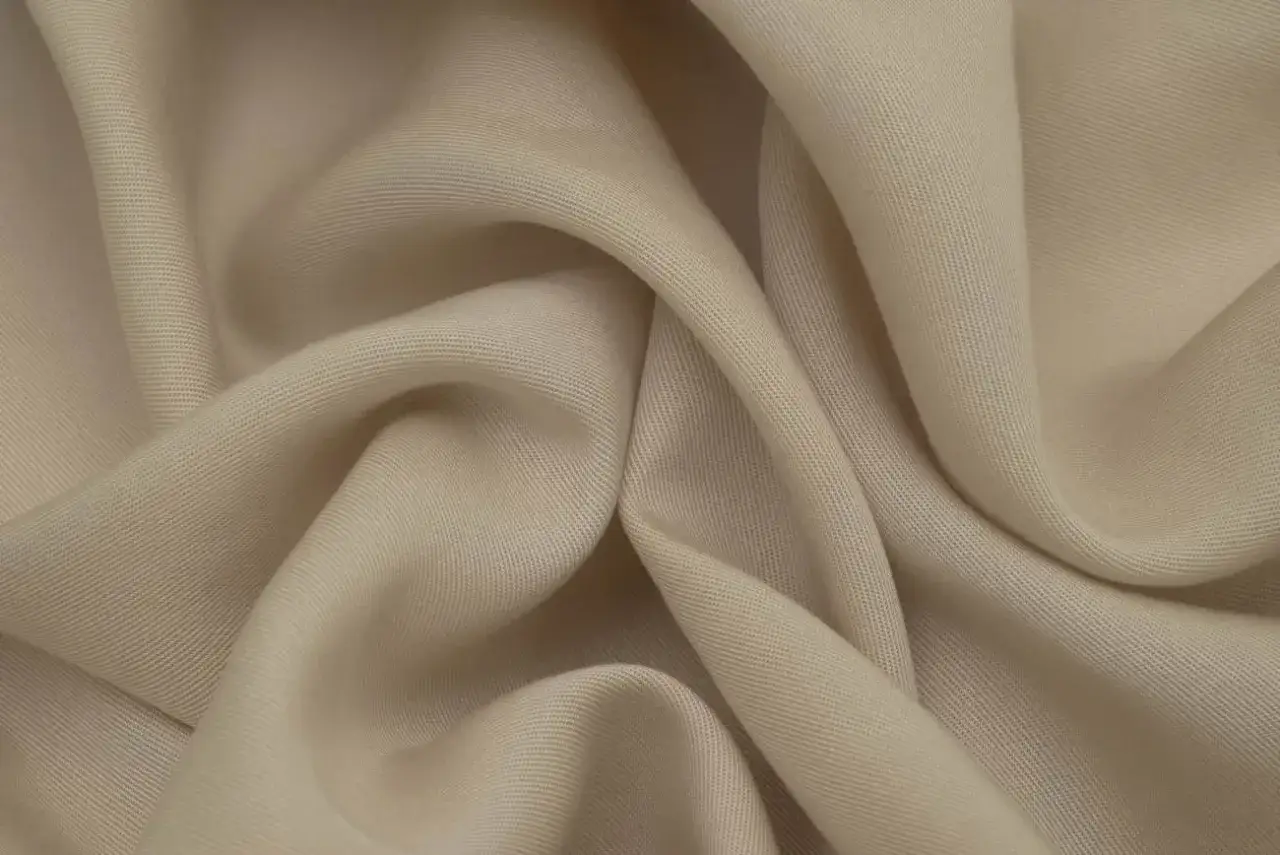 Miękka, beżowa tkanina Tencel, układająca się w eleganckie fałdy. Dowiedz się, tencel co to za materiał.