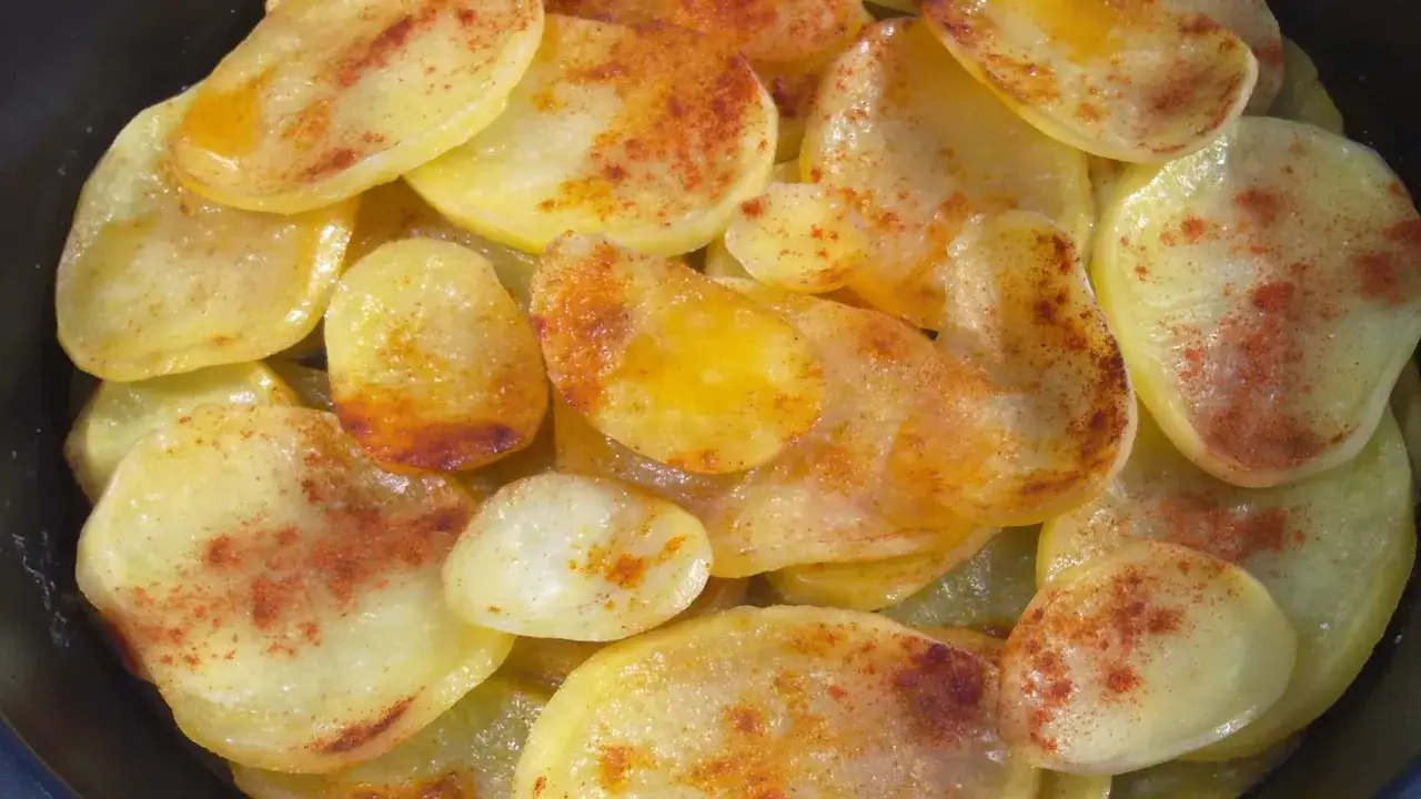 Rodajas de patatas fritas al horno, doradas y espolvoreadas con pimentón, listas para disfrutar.