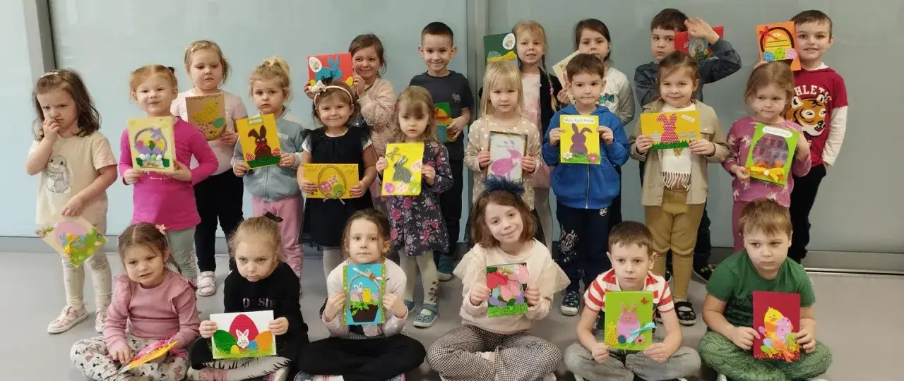 Dzieci prezentują wielkanocne kartki wykonane podczas wolontariatu w przedszkolu.