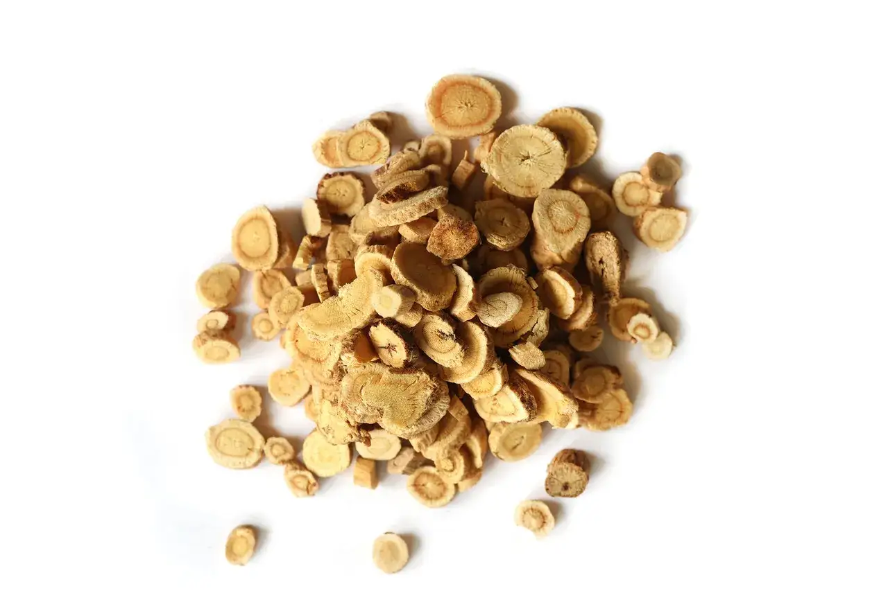 Un tas de rondelles de racine d'astragale séchée, connues pour leurs nombreux bienfaits pour la santé, sur fond blanc.