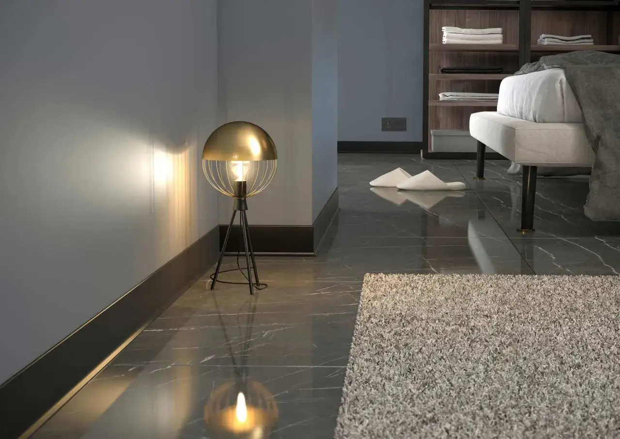 L&aacute;mpara dorada ilumina rodapi&eacute;s modernos y suelo de m&aacute;rmol. Zapatillas y alfombra mullida a&ntilde;aden confort.