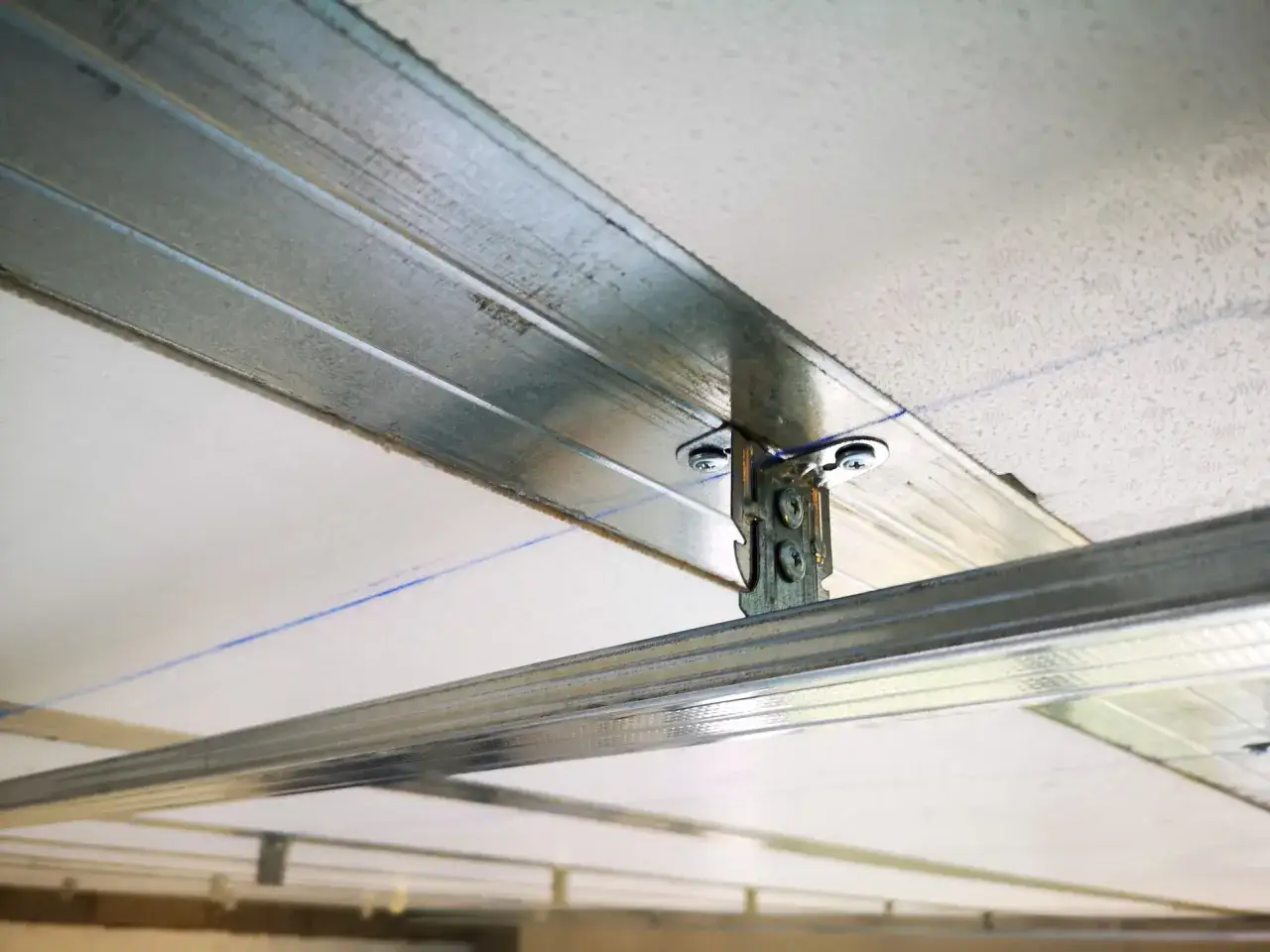 Structure métallique pour un faux plafond, avec un élément de fixation visible. Ce kit fixation plafonnier assure la solidité de l'ensemble.