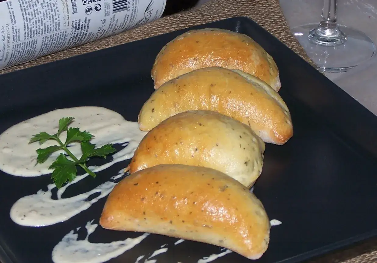 Złociste, pieczone pierożki drożdżowe z ziołami, podane z sosem i natką pietruszki. Idealne, gdy pieczesz ciasto drożdżowe w temperaturze 180°C.