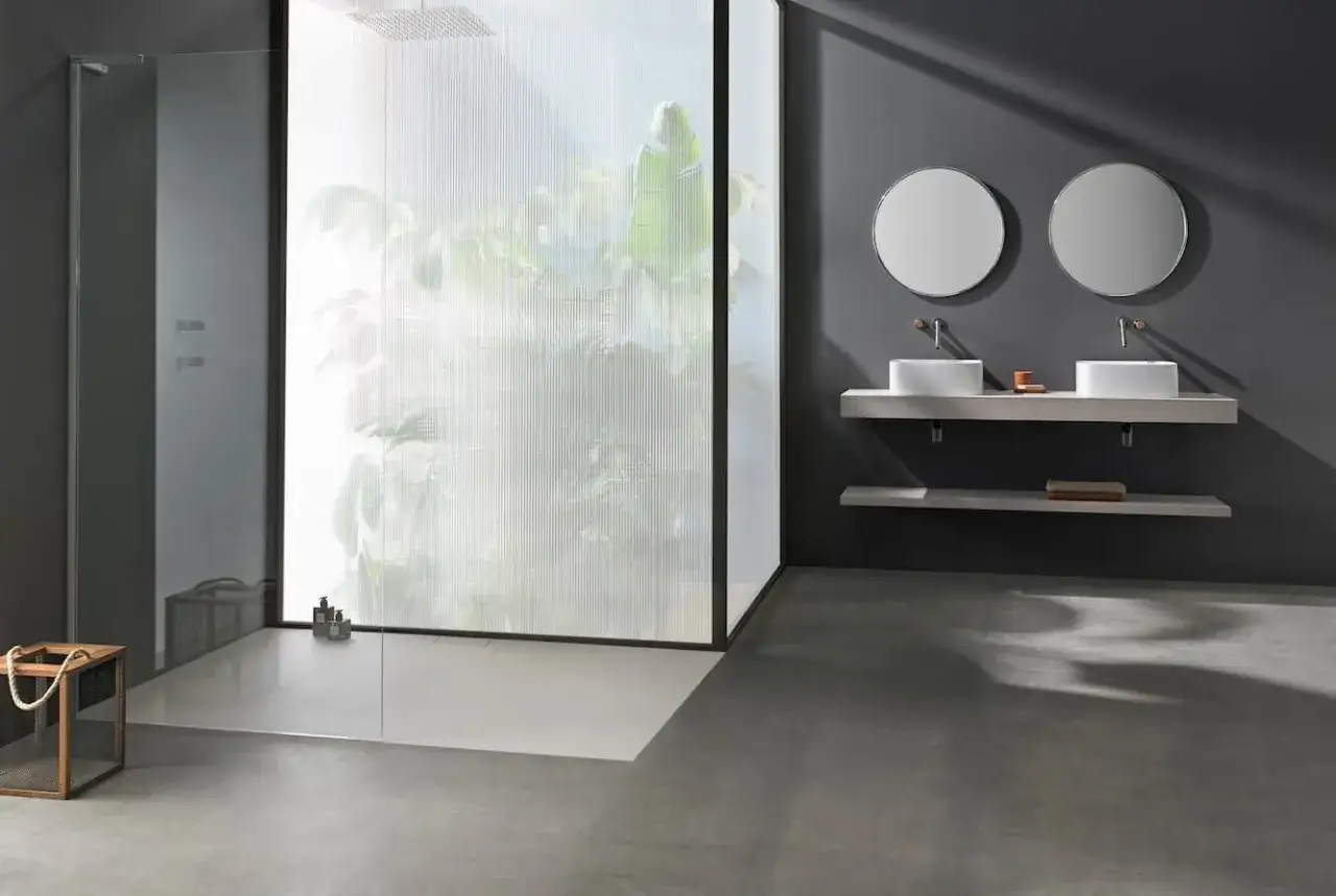 Modern bathroom with dual sinks and **duchas sin mampara** featuring a frosted glass enclosure with lush greenery visible.
