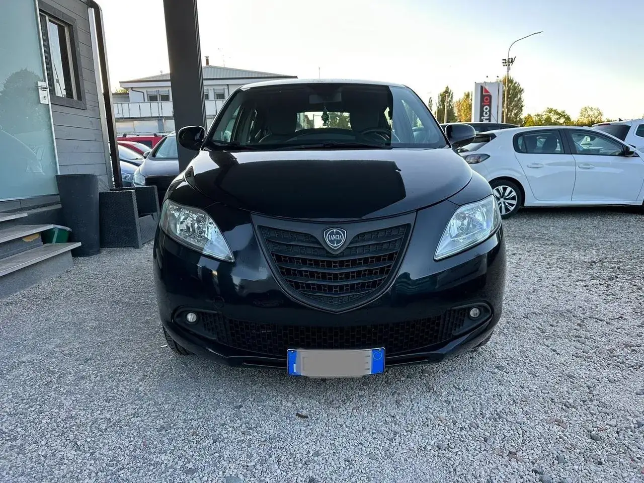 Lancia Ypsilon a metano, nera, vista frontale, parcheggiata su ghiaia.
