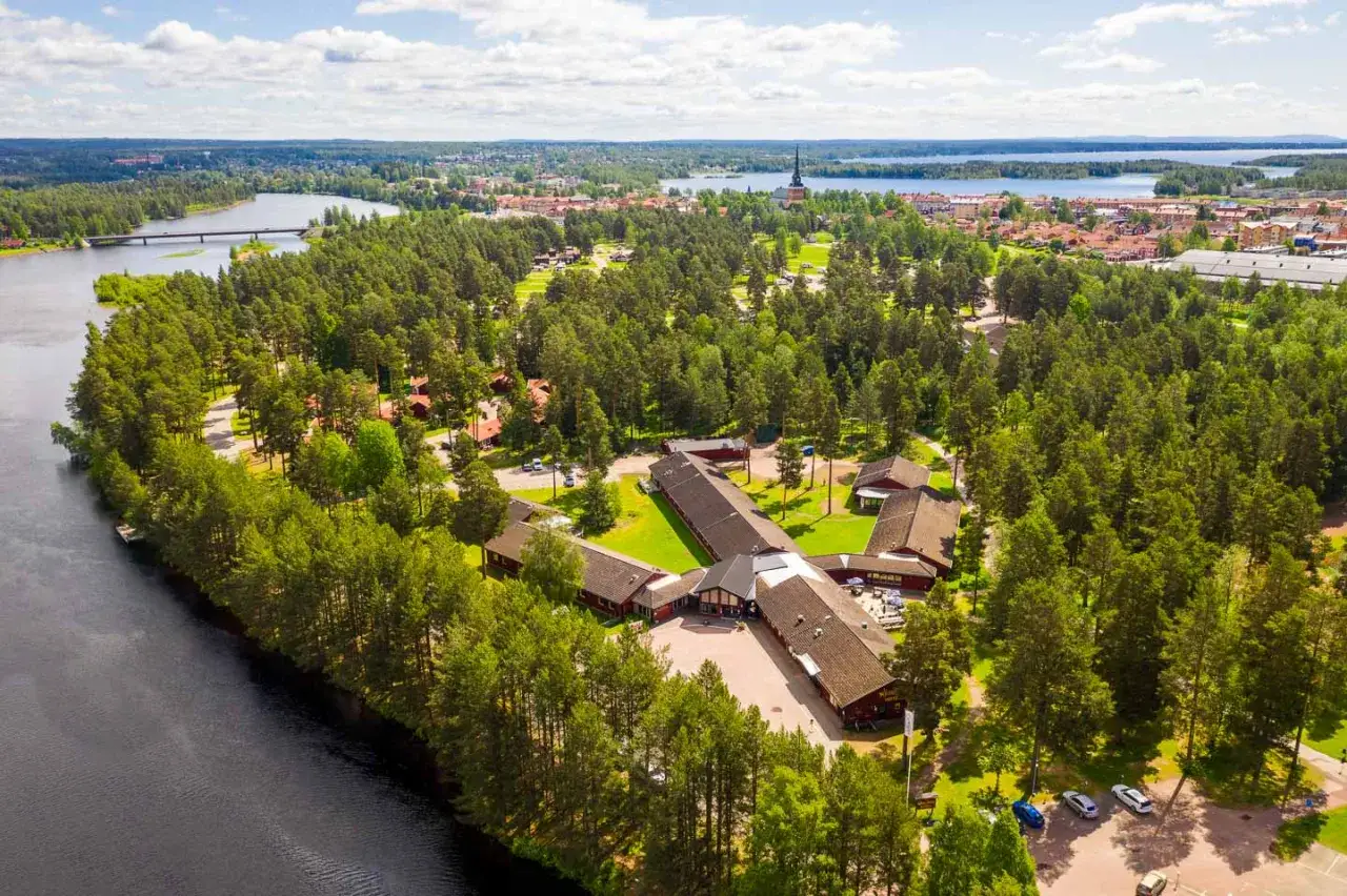 Vacker vy över Moraparken Camping med sjö, skog och stad i bakgrunden.