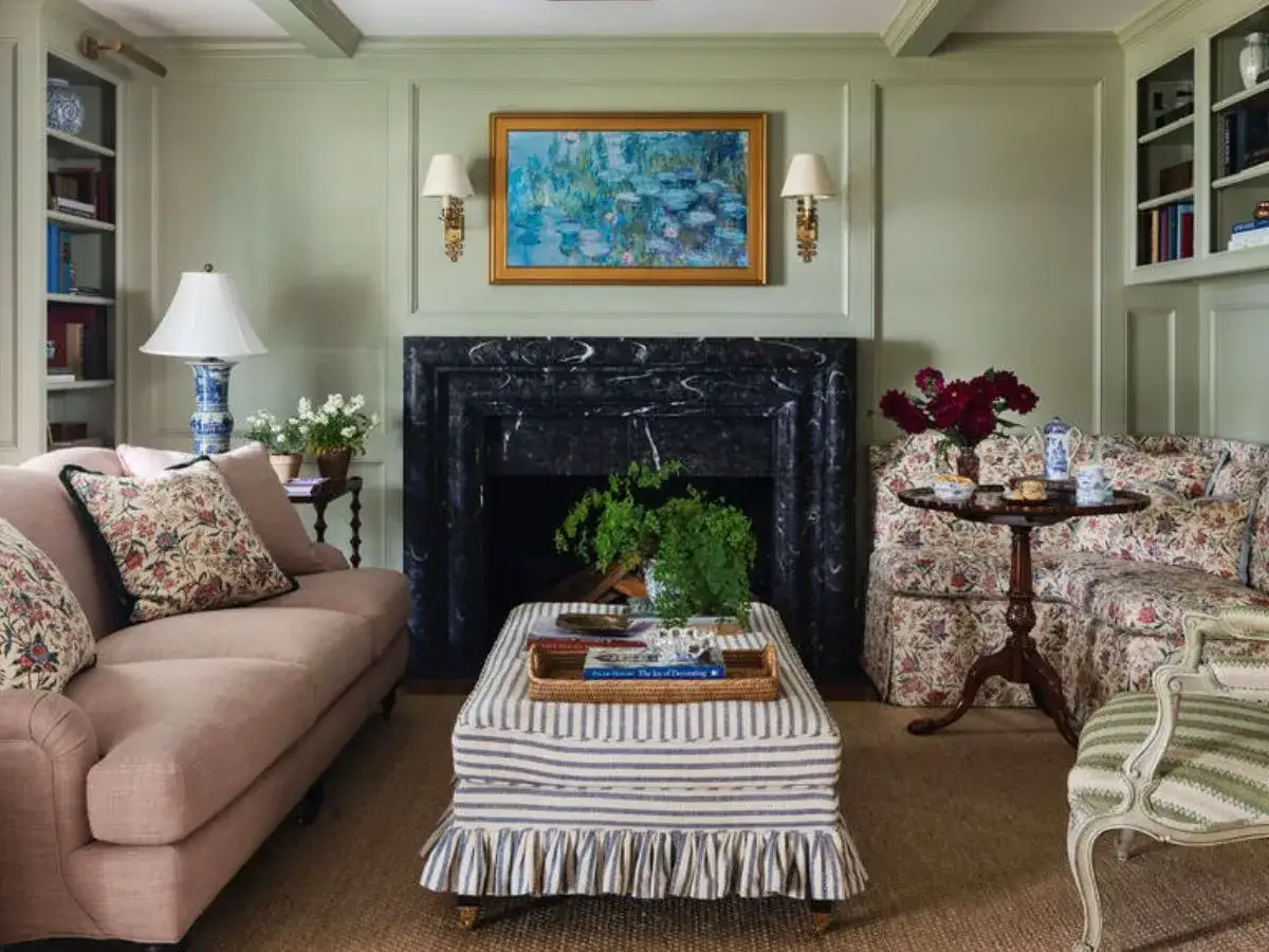 A cozy living room with various furniture styles, featuring a floral sofa, a striped ottoman, and a classic armchair.
