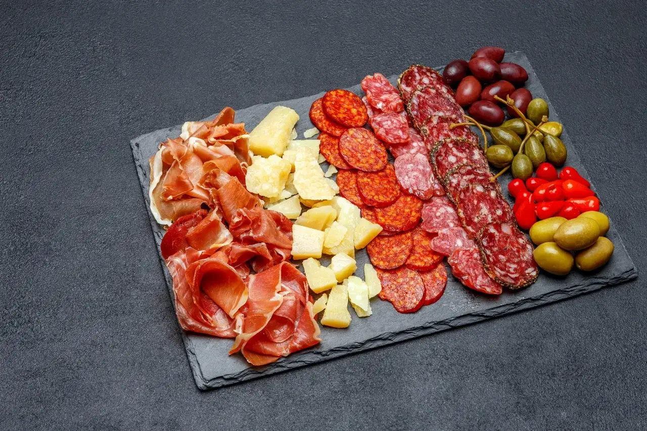 Tabla de embutidos: jamón serrano, quesos, chorizo, y que es el salami, aceitunas y alcaparras.