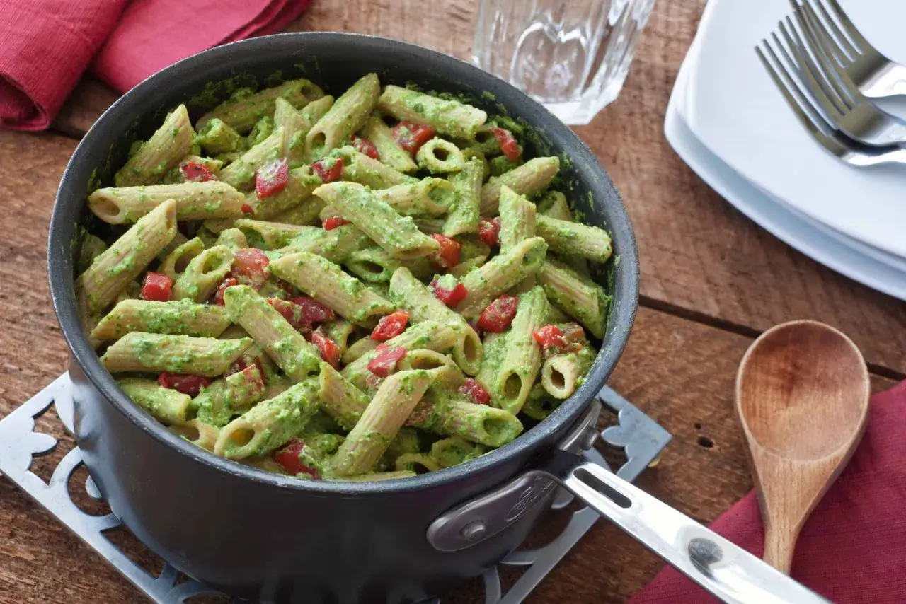 Penne z sosem szpinakowo-serowym i kawałkami pomidora w garnku. Idealne danie na szybki obiad.