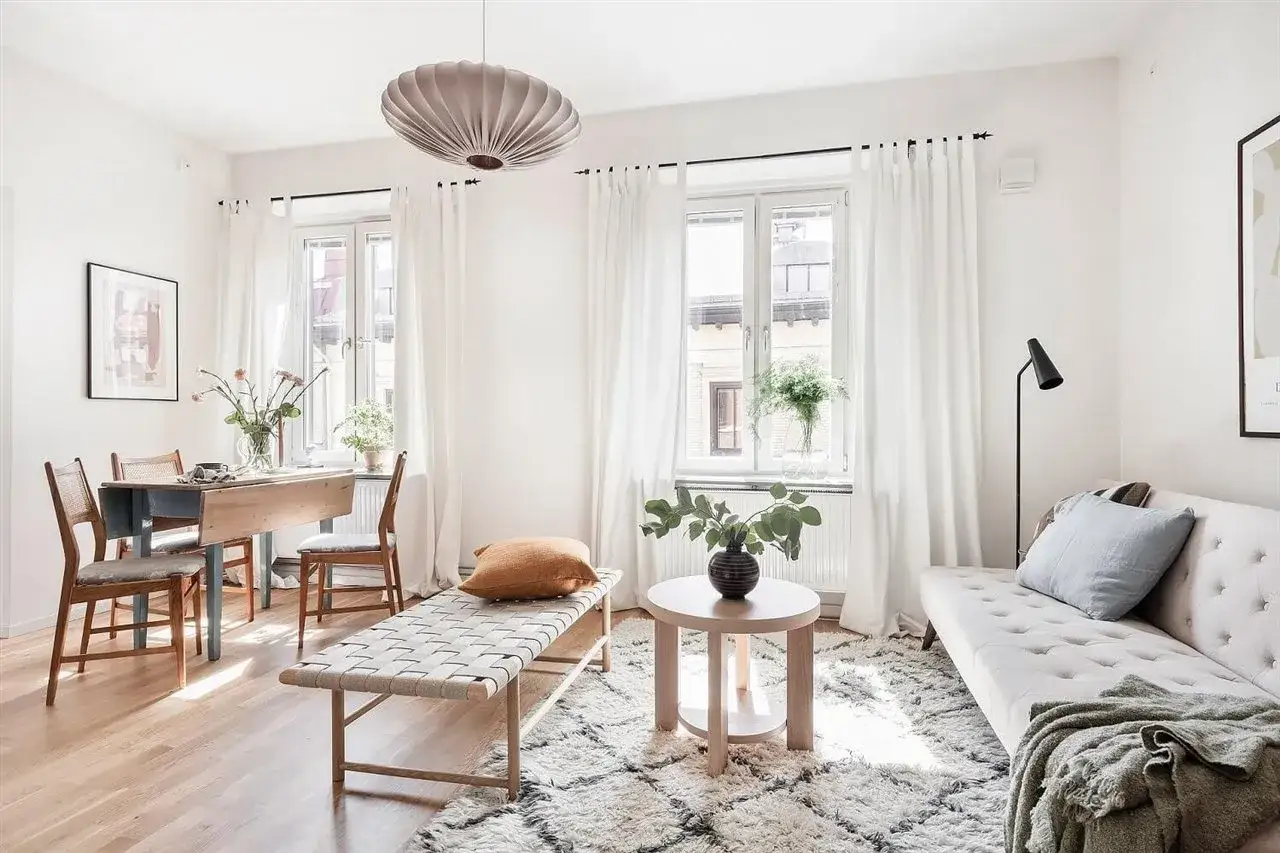 Salones con alfombras acogedoras, un sof&aacute; blanco, mesa de comedor y banco de madera.