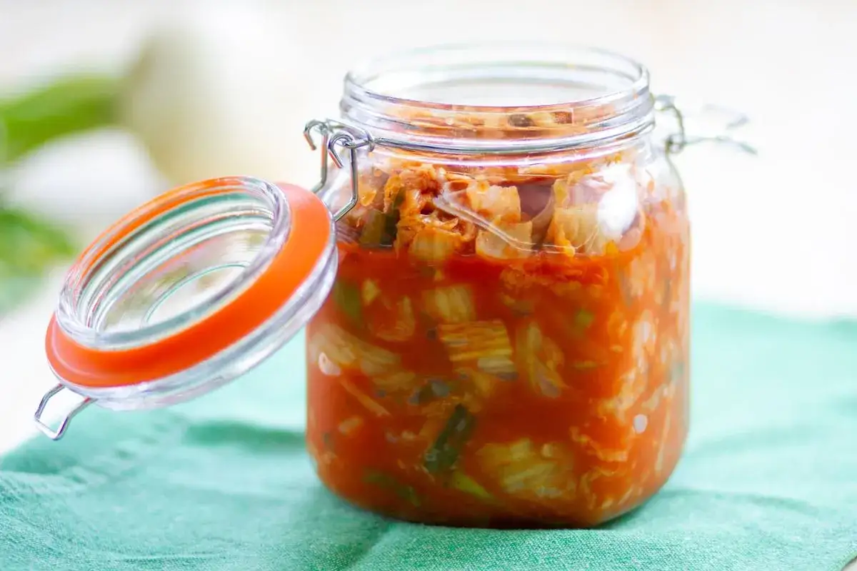 Słoik z domowym kimchi, którego intensywny kolor sugeruje obecność sosu gochujang.