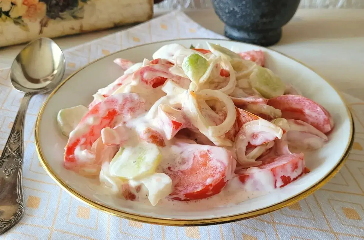 Pyszne pomidory ze śmietaną i ogórkiem, doprawione cebulką. Idealna letnia przekąska.
