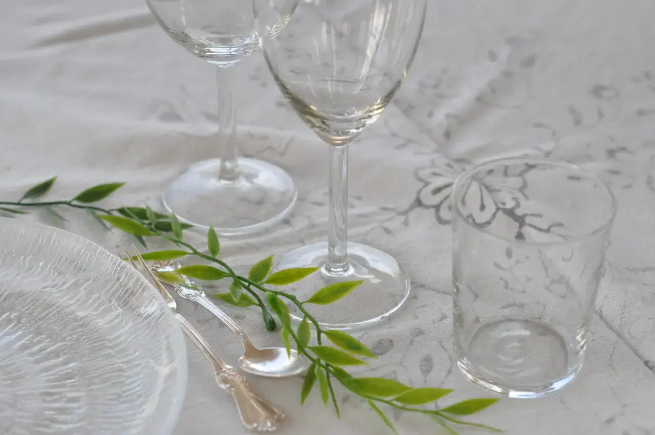 Vackert dukat med glas, tallrik och bestick. Gr&ouml;na blad ger en fin detalj. H&auml;r ser du hur glasen placeras vid dukning.