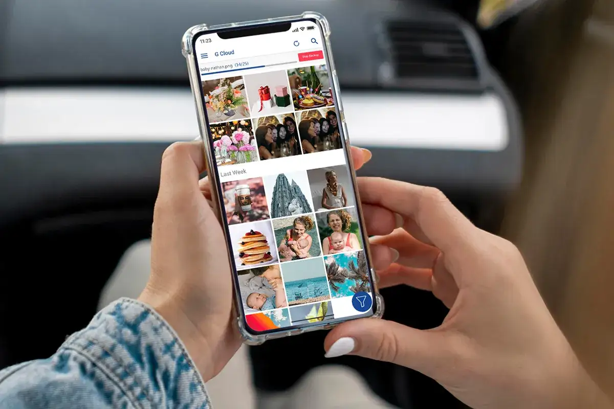 En person håller en mobil som visar G Cloud-appen med bilder. Perfekt för att spara bilder från mobilen och organisera minnen.