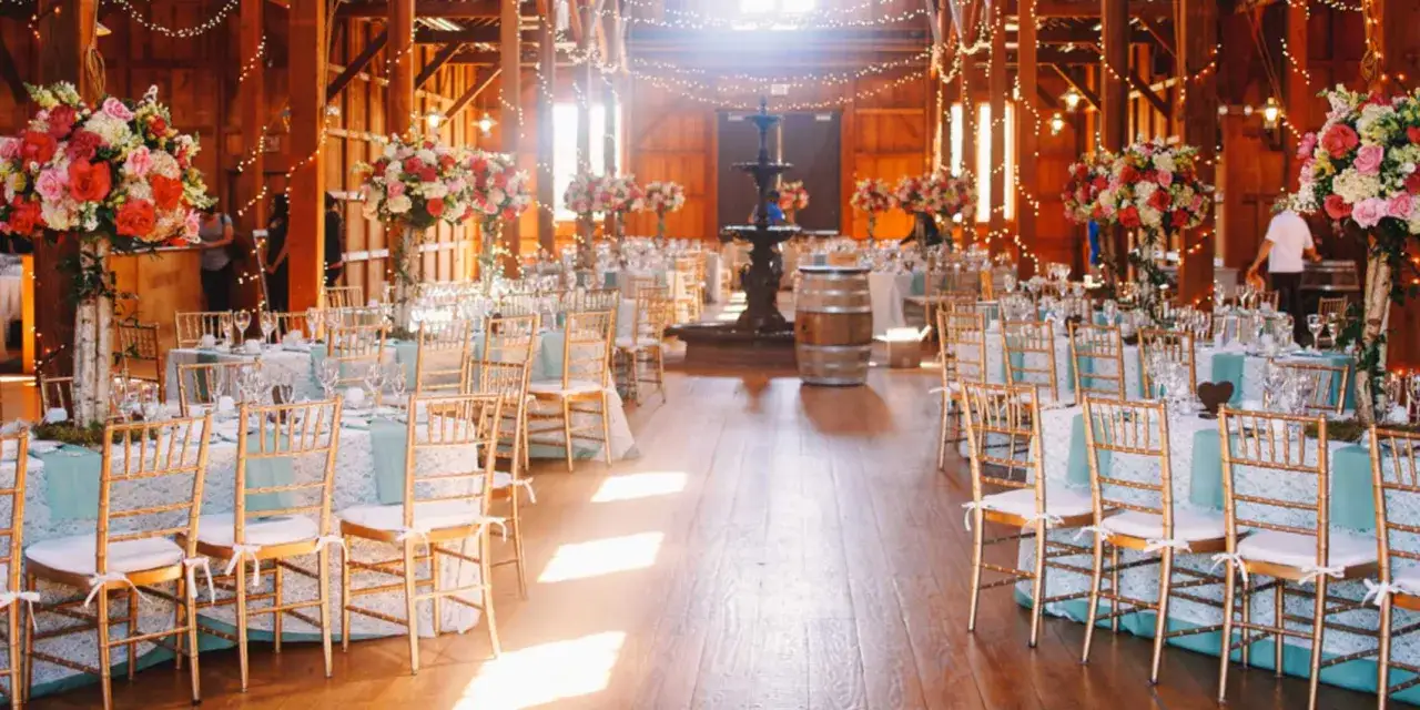 Magnifique salle de réception de mariage avec un plan de table en épi, décorée de fleurs et de lumières scintillantes.