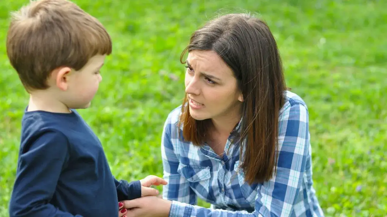 Zmartwiona mama rozmawia z synkiem na trawie. Co zrobić, gdy 3 latek nie słucha?