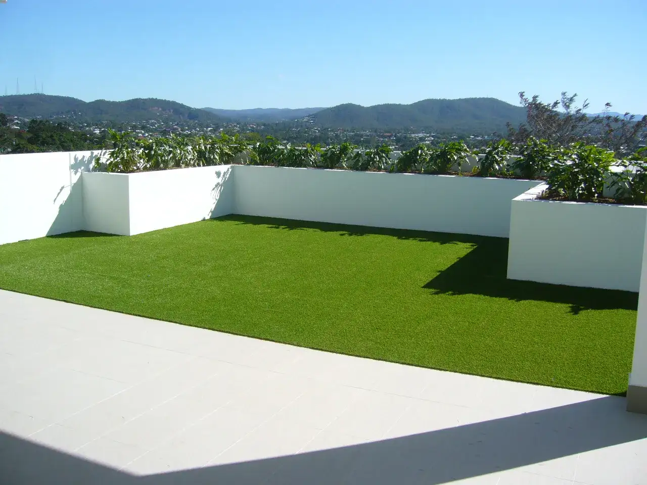 Terraza con césped artificial verde vibrante, ideal para aprender como colocar césped artificial y disfrutar de vistas panorámicas.