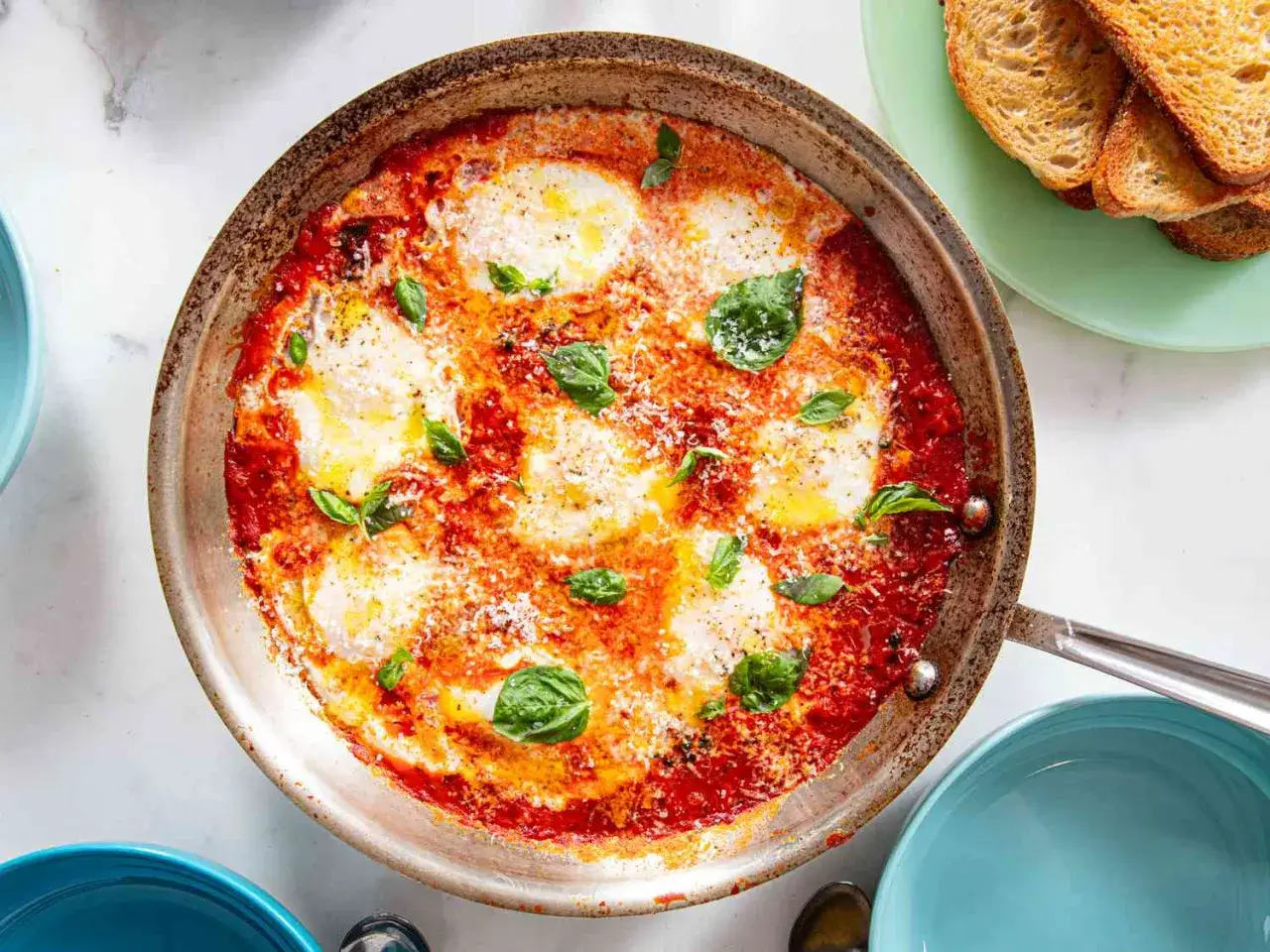 Herzhafte eier in tomatensauce, italienisch gew&uuml;rzt, mit frischem Basilikum und Parmesan bestreut. Dazu ger&ouml;stetes Brot.