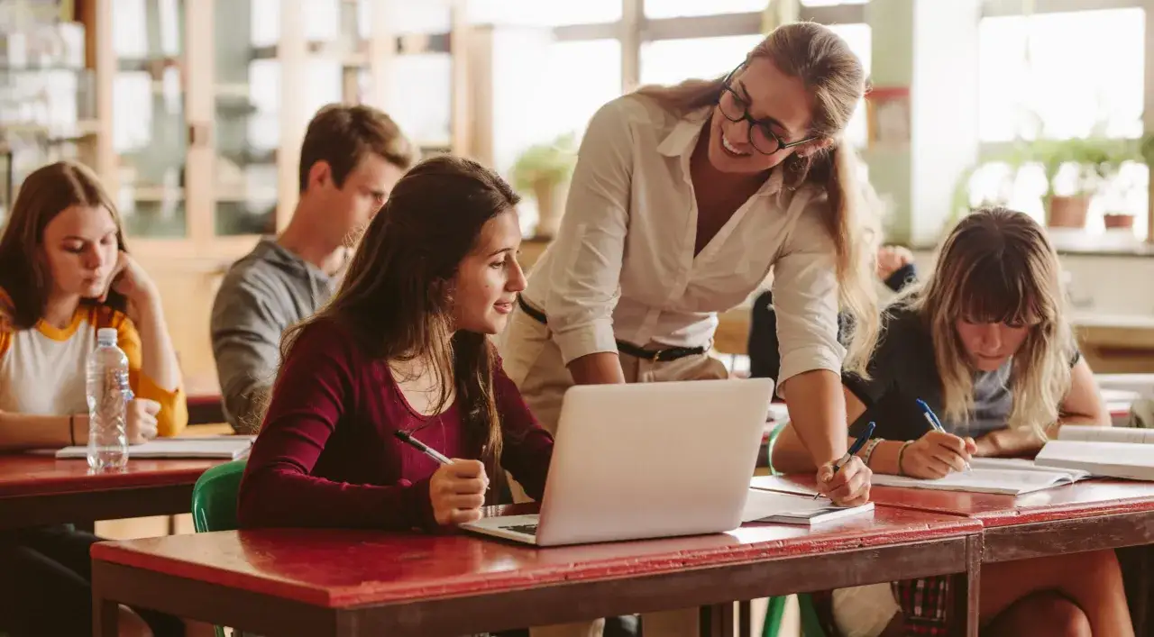 Nauczycielka pomaga studentom podczas zajęć, które mogą być częścią studiów online pedagogika.