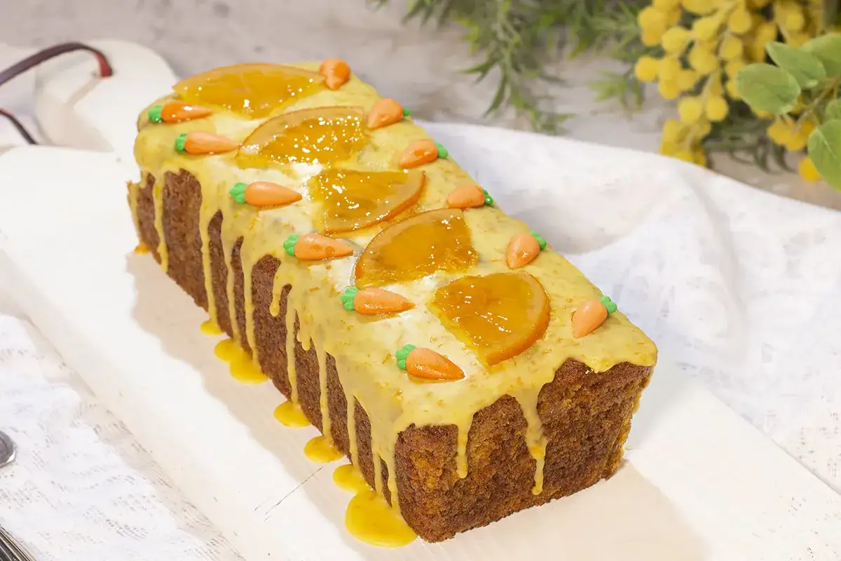 Pastel de zanahoria con glaseado naranja, decorado con rodajas de naranja y zanahorias de mazapán. Una deliciosa carrot cake receta original inglesa.