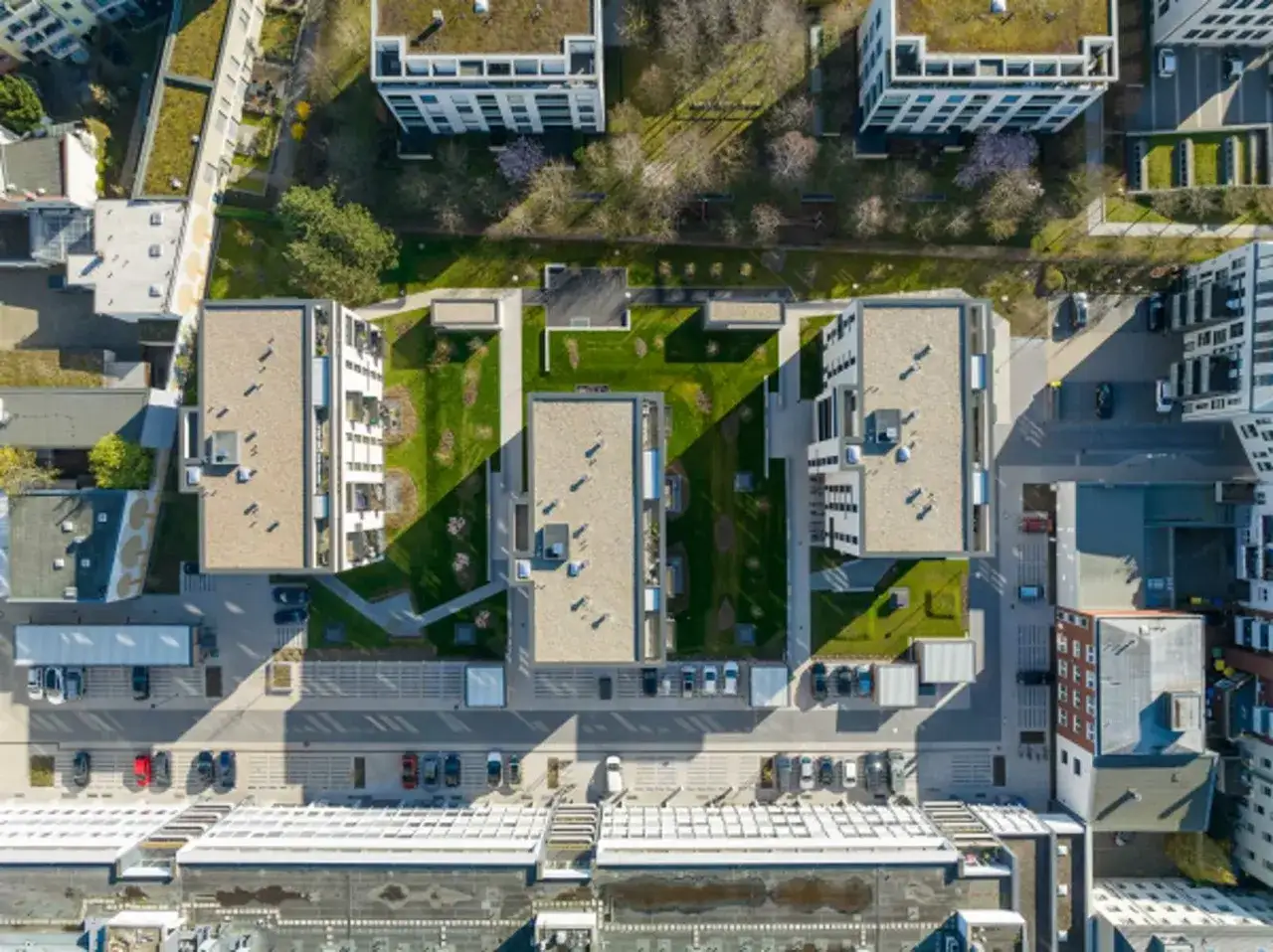 Moderne Wohnanlage im **Vorort** mit begrünten Dächern, gepflegten Grünflächen und Parkplätzen.